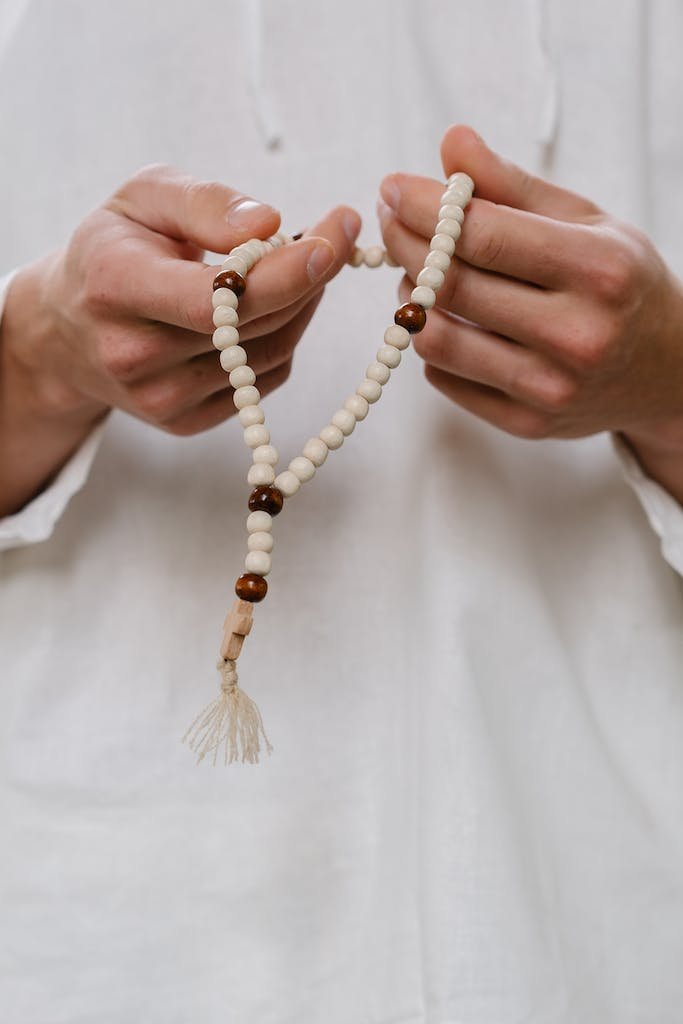 Person in White Dress Shirt Wearing White Beaded Bracelet